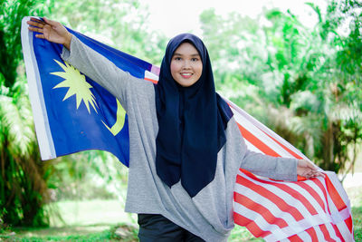 Muslim woman happy holding a malaysian flag. malaysia independence day.