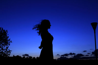 Silhouette woman standing against blue sky