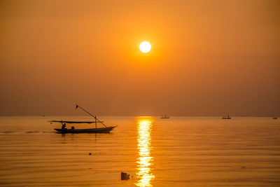 Silhouette boats in sea against orange sky