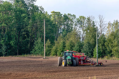 Tractor on road amidst trees in forest against sky