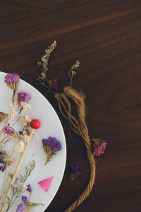 Directly above shot of rope by dried flowers on wooden table