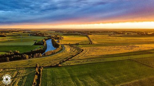 Scenic view of agricultural field against sky during sunset