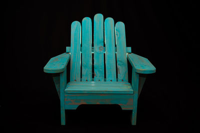 Close-up of blue chair against black background