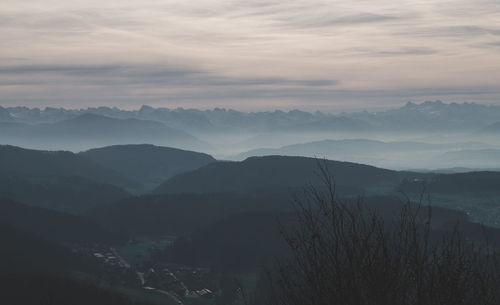 Scenic view of mountains against cloudy sky in foggy weather