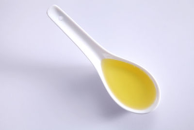 High angle view of cooking oil in spoon over white background