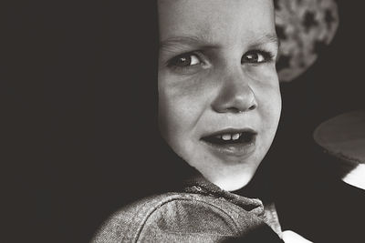 Portrait of smiling boy against black background