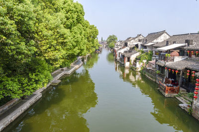 River amidst buildings and trees against sky