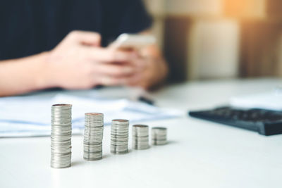 Cropped image of hand holding coin stack on table