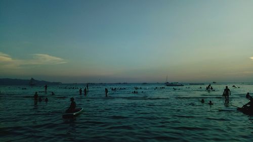 Silhouette people enjoying in sea against sky