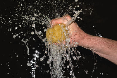 Close-up of man splashing water against black background