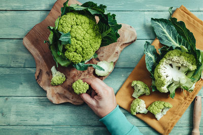 High angle view of hand holding vegetables on table