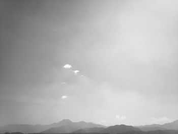 Low angle view of sunlight streaming through clouds