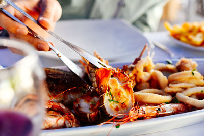 Cropped hand of person holding seafood with serving tong