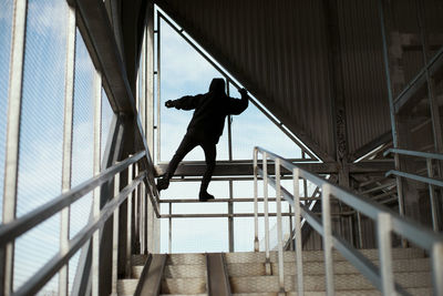 Low angle view of silhouette man standing on staircase of building