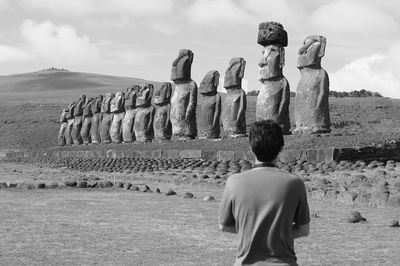 Monochrome of massive moai statues of ahu tongariki with visitor in foreground, easter island, chile