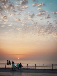 People on beach against sky during sunset