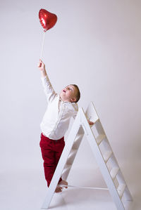 Portrait of boy playing with balloons against wall