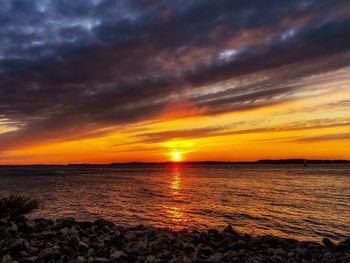 Scenic view of sea against dramatic sky during sunset