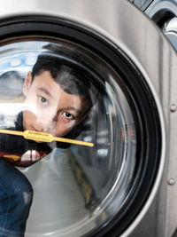 Portrait of a young man behind the washing machine glass cover