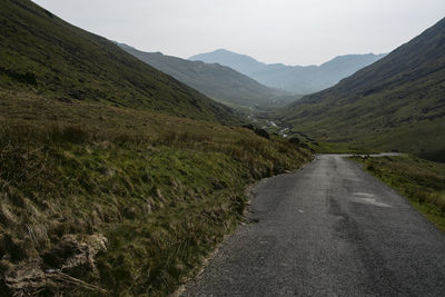 Road leading towards mountains against sky