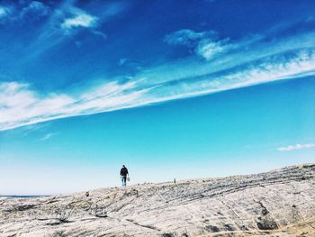 Man climbing on mountain against blue sky