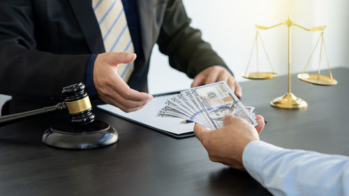 Midsection of man holding hands and coffee cup on table