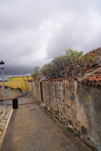 Footpath by retaining wall against sky