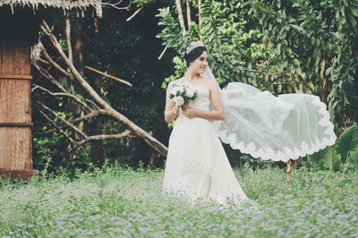 Bride wearing wedding dress while standing on grassy field at park