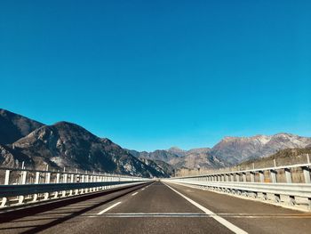 Road leading towards mountains against clear blue sky.  from italy to slovenia