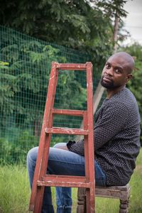 Portrait of man sitting by ladder
