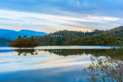 Scenic view of lake by trees against sky