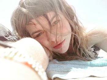 Close-up portrait of young woman lying on blanket during sunny day