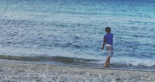 Rear view of boy standing on beach