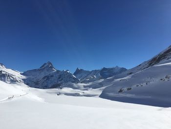 Scenic view of snowcapped mountains against clear blue sky