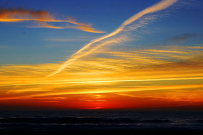 Scenic view of sea against dramatic sky during sunset