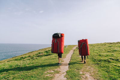 People with mattress walking at beach against sky