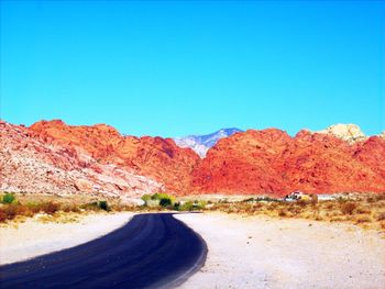 Road by mountain against clear blue sky