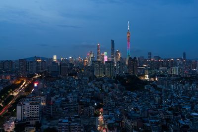 Illuminated modern buildings in city against sky at night