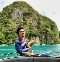 Young man sitting on boat in sea