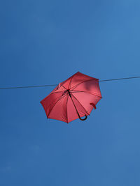 Low angle view of umbrella against clear blue sky