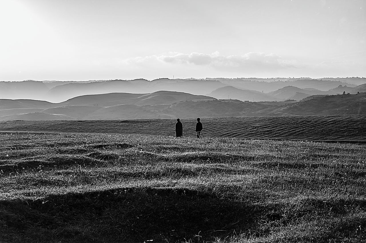 leisure activity, lifestyles, landscape, men, tranquil scene, walking, tranquility, sky, scenics, sand, full length, nature, mountain, beauty in nature, unrecognizable person, vacations, person