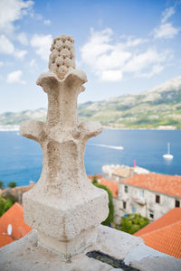 Close-up of cross sculpture against sea