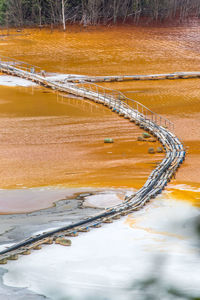 High angle view of pipe on bridge amidst dirty lake