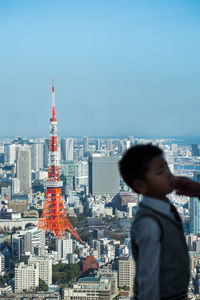 Rear view of man looking at city buildings against sky
