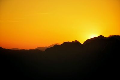 Scenic view of silhouette mountains against orange sky