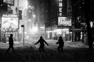 Silhouette people on illuminated street at night