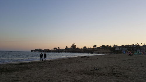 Men at beach against sky during sunset