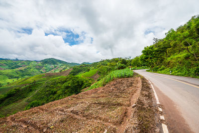 Road amidst green landscape against sky