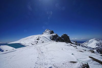 Scenic view of snowcapped mountains against blue sky