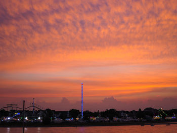 Silhouette factory against orange sky